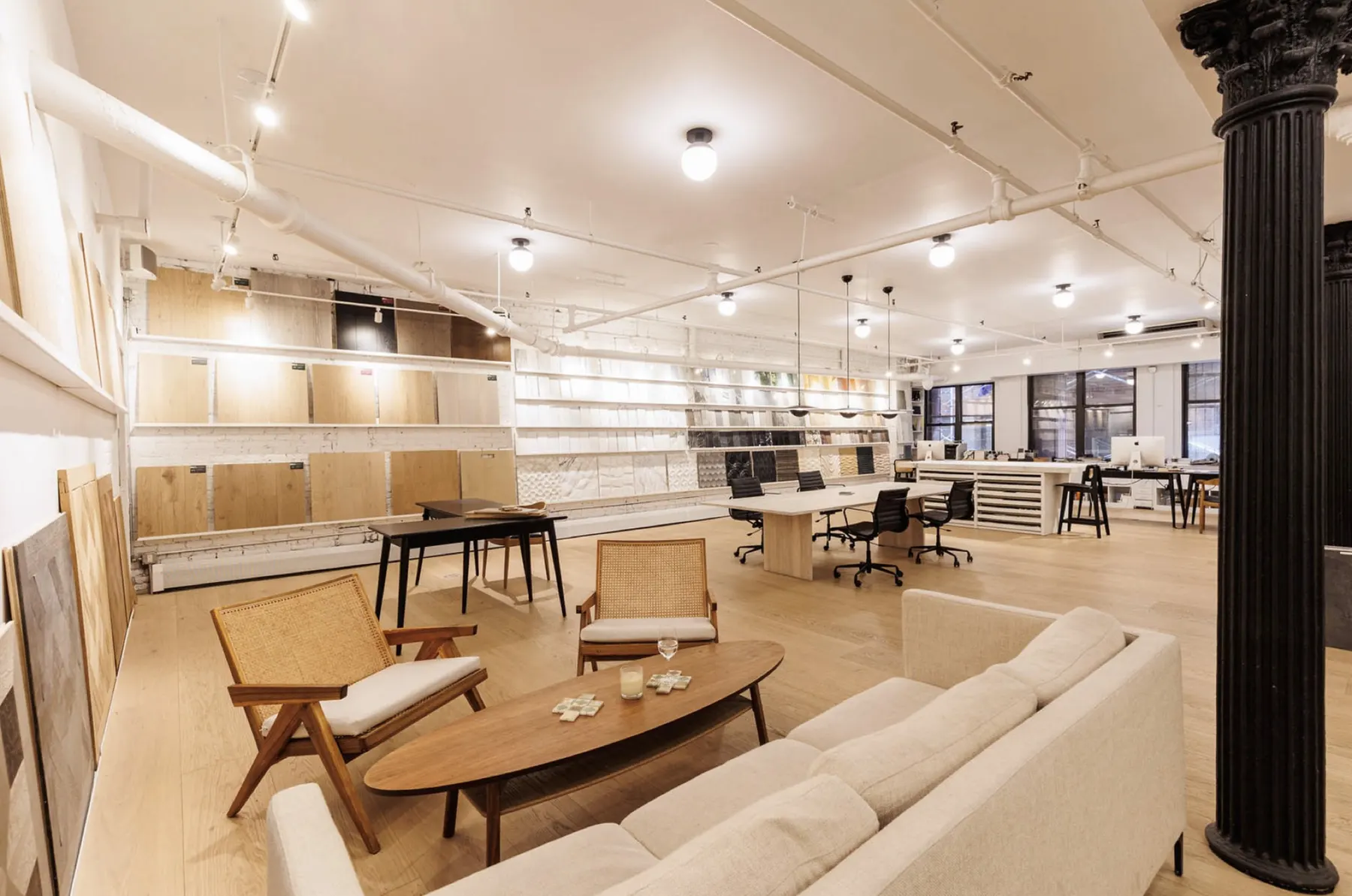 The Tribeca Stone showroom: a lower-level loft with a cast-iron column, a lounge, wood panels and walls of tile samples